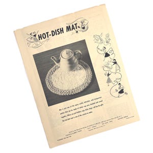 May include: A vintage advertisement for a hot-dish mat. The image features a teapot on a round, braided mat. The text reads "HOT-DISH MAT" and describes the mat as easy to make. The ad is in black and white.