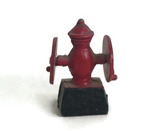 May include: A miniature red metal coffee grinder with black base and two wheels.