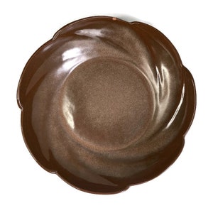 May include: A brown ceramic bowl with a scalloped edge and a swirl design. The bowl is glazed with a brown and gold color.