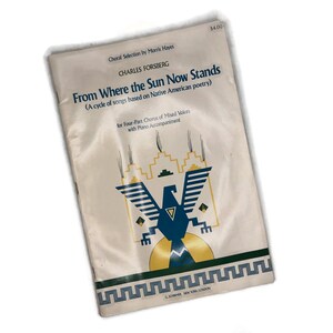 Op de afbeelding: Een wit boekje met een blauw en geel adelaarontwerp. De titel is "From Where the Sun Now Stands" van Charles Forsberg. Het is een cyclus van liederen gebaseerd op Native American poëzie voor vierdelig koor van gemengde stemmen met pianobegeleiding.