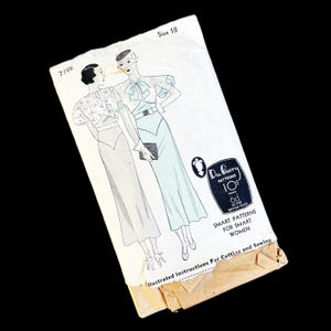 May include: A vintage Du Barry sewing pattern envelope, number 739B, size 18. The white paper envelope features a black and white illustration of a dress with a bow, a belt, and puffed sleeves. Text includes Du Barry Patterns, 10 cents, and Smart Patterns for Smart Women.