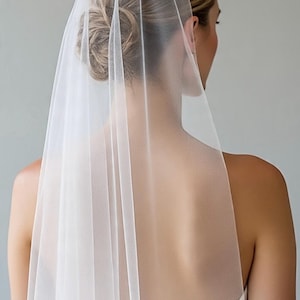 May include: A sheer white bridal veil made of fine tulle fabric, draped elegantly over the back of the head and shoulders. The veil features a smooth, lightweight texture that falls vertically, creating a soft and translucent appearance.