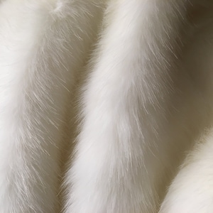 May include: Close-up of a white fur texture. The fur appears soft and fluffy, with long, flowing strands. The color is a bright, clean white, and the texture is dense and luxurious.