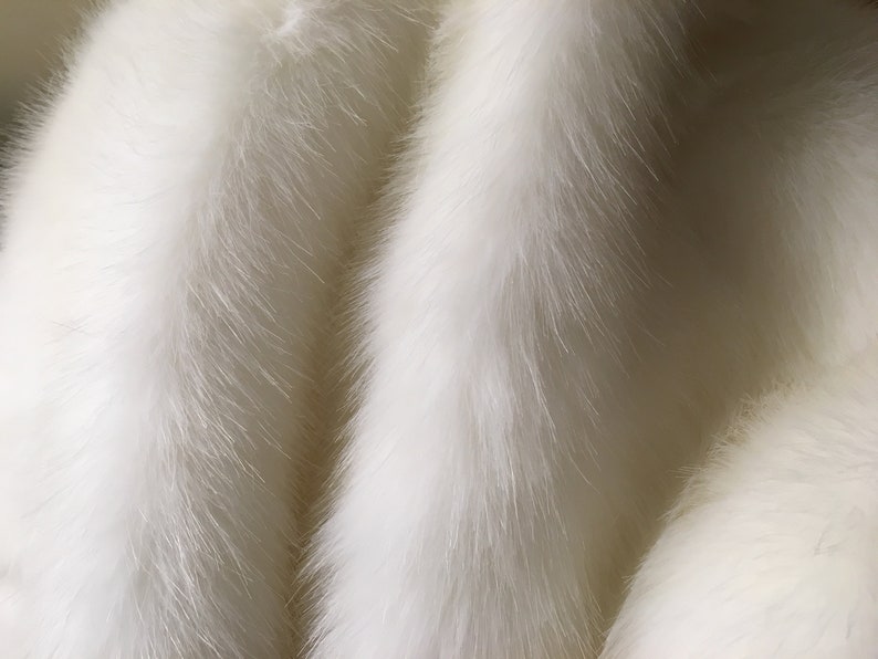 May include: Close-up of a white fur texture. The fur appears soft and fluffy, with long, flowing strands. The color is a bright, clean white, and the texture is dense and luxurious.