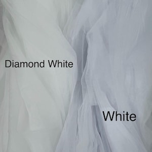 May include: Two layers of sheer, fine-mesh tulle fabric displayed side-by-side. The left section is labeled Diamond White, and the right section is labeled White. The fabric has a soft, translucent texture with visible folds and gathers.