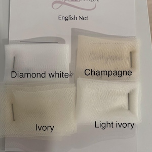 May include: A display card from L&T Couture Bridal Boutique featuring four swatches of English Net fabric pinned in place. The colors are labeled as Diamond white, Champagne, Ivory, and Light ivory, showcasing the different net fabric shades.