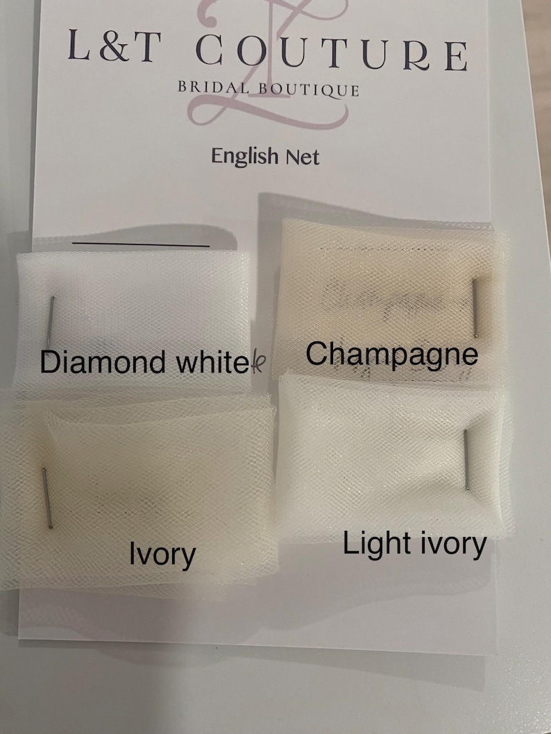 May include: A display card from L&T Couture Bridal Boutique featuring four swatches of English Net fabric pinned in place. The colors are labeled as Diamond white, Champagne, Ivory, and Light ivory, showcasing the different net fabric shades.