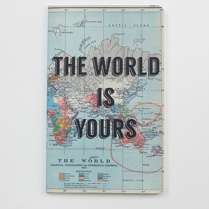 May include: A vintage world map with the text "THE WORLD IS YOURS" printed over it. The map shows colonial possessions and commercial highways from 1910.
