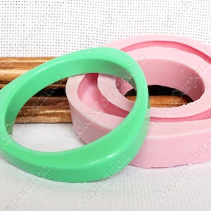 Könnte beinhalten: Ein hellgrünes, quadratisch geformtes Armreif-Armband neben einer rosa, ringförmigen Form. Das Armband hat eine strukturierte Oberfläche. Die Form besteht aus Silikon und ist für die Schmuckherstellung bestimmt.