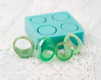 May include: A teal silicone ring mould with four circular cavities, alongside three translucent green resin rings with gold flecks. The rings vary in shape and size, demonstrating the mould's versatility for jewellery making.