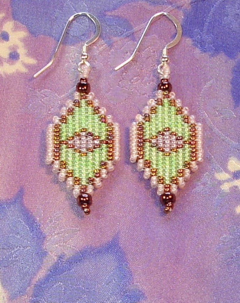 May include: A pair of green, brown, and white beaded earrings with silver hooks. The earrings are shaped like a diamond and have a geometric pattern.