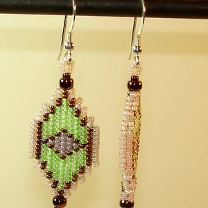 May include: A pair of green, brown, and white beaded earrings with silver hooks. The earrings are shaped like a diamond and have a geometric pattern.
