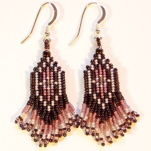 Peut inclure: Une paire de boucles d'oreilles perl&eacute;es avec des crochets argent&eacute;s. Les boucles d'oreilles pr&eacute;sentent un motif g&eacute;om&eacute;trique dans les tons noir, rose et blanc. La frange perl&eacute;e est en forme d'&eacute;ventail, cr&eacute;ant un design d&eacute;licat et &eacute;l&eacute;gant.