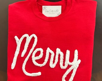 May include: Red sweatshirt with white fluffy lettering that says "Merry".