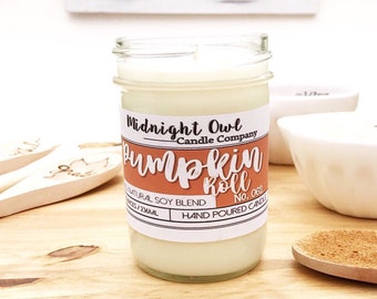Puede incluir: Una vela en un tarro de vidrio con una etiqueta blanca que dice "Midnight Owl Candle Company Pumpkin Roll No. 062 Natural Soy Blend Hand Poured Candle".