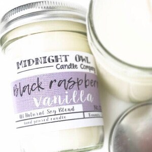 May include: A glass jar candle with a purple and white label that reads "Midnight Owl Candle Company Black Raspberry Vanilla 100% Natural Soy Blend Hand Poured Candle".