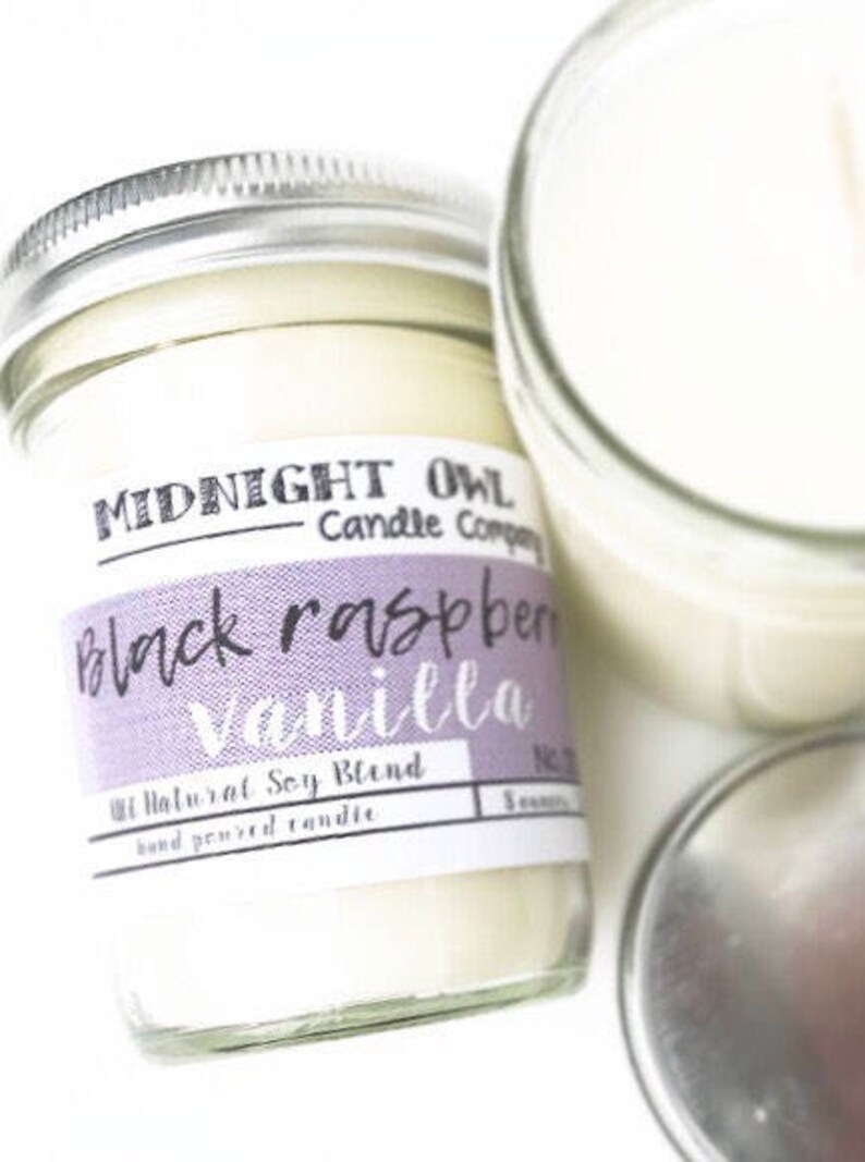 May include: A glass jar candle with a purple and white label that reads "Midnight Owl Candle Company Black Raspberry Vanilla 100% Natural Soy Blend Hand Poured Candle".