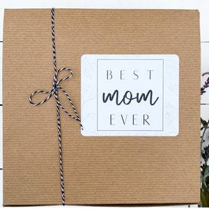 May include: A brown cardboard box with a white label that says "BEST mom EVER". The box is tied with a black and white twine.