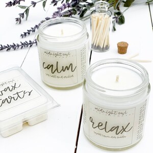 May include: Two glass candle jars with white wax and wooden wicks. The jars have labels that read "midnight owl candles" and the scents "calm sea salt and orchid" and "relax sweet lavender buds".