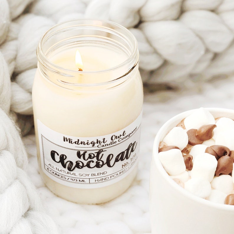 K&ouml;nnte beinhalten: Eine wei&szlig;e Kerze in einem durchsichtigen Glasgef&auml;&szlig; mit einem schwarzen Etikett, auf dem "Midnight Owl Candle Company Hot Chocolate All Natural Soy Blend 8 ounces/473 ml Hand Poured No. 102" steht.