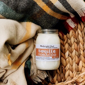 May include: A glass jar candle with a white label that reads "Midnight Owl Candle Company" and "Vanilla Tobacco No. 031". The label also states "All Natural Soy Blend" and "8 ounces/473 ml Hand Poured Candle".