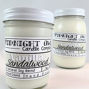 May include: Two glass jars with white lids containing soy candles. The labels are white with black text that reads "Midnight Owl Candle Company" and "Vanilla Sandalwood". The jars are 8 ounces/236 ml and hand-poured.