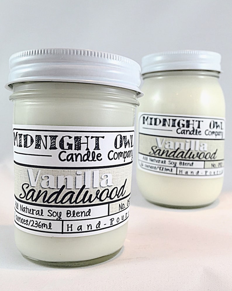 May include: Two glass jars with white lids containing soy candles. The labels are white with black text that reads "Midnight Owl Candle Company" and "Vanilla Sandalwood". The jars are 8 ounces/236 ml and hand-poured.