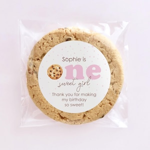 May include: A round cookie with a pink and white sticker that says "Sophie is one sweet girl. Thank you for making my birthday so sweet!"