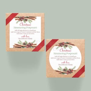 Peut inclure: Deux boîtes carrées sur le thème de Noël. Chaque boîte porte une étiquette avec le texte "Christmas Simmering Potpourri" et des instructions. Les boîtes sont décorées de bâtons de cannelle, de pommes de pin et de rubans rouges.