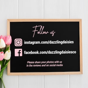 May include: Black chalkboard with white wooden frame, displaying social media handles for "dazzlingdaisies" on Instagram and Facebook. The text "Follow us" is written in pink cursive above the handles. The text "Please share your photos with us in the reviews and on social media" is written in white below the handles.