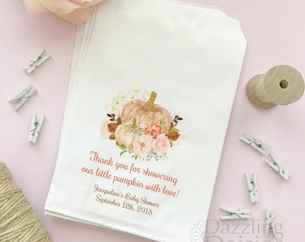 May include: White paper favor bags with a pumpkin and floral design. The bags have text that reads "Thank you for showering our little pumpkin with love!" and "Jacqueline's Baby Shower September 12th, 2018."