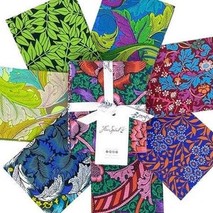 May include: A set of eight fabric squares featuring various floral patterns in shades of green, blue, red, and purple. The fabric squares are arranged in a circle with a white tag in the center that reads "Fine Spiral".