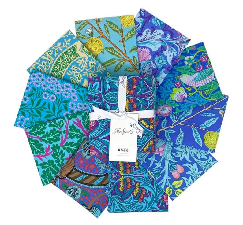 May include: A set of eight fabric squares featuring a variety of floral and botanical patterns in shades of blue, green, and purple. The fabric squares are arranged in a circle and have a white label with the text "Free Spirit" in the center.