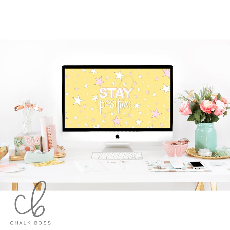 May include: A yellow desktop background with white and pink stars and the text "STAY positive" in pink and white lettering. The background is displayed on a computer monitor on a white desk.