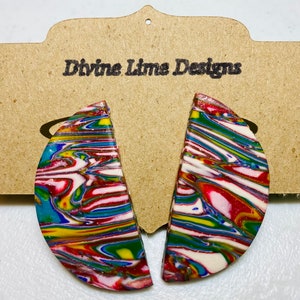 May include: A pair of colorful, half-circle earrings with a marbled pattern in shades of red, white, blue, green, and yellow. The earrings are displayed on a brown card with the text "Divine Lime Designs".