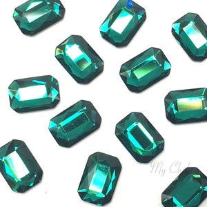 May include: Emerald green rectangular rhinestones with a faceted finish. The rhinestones have a slight iridescent shimmer.
