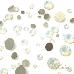 Puede incluir: Surtido de piedras de cristal de ópalo blanco de varios tamaños, esparcidas sobre un fondo blanco.