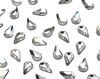 May include: A scattering of clear teardrop-shaped rhinestones on a white background.