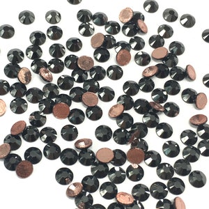 Può includere: Una spolverata di strass neri con retro in rame. Gli strass sono sfaccettati e hanno una finitura lucida.