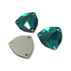 May include: Three emerald green sew-on rhinestones with three holes each. The rhinestones are faceted and have a shiny finish. The rhinestones are on a white background.