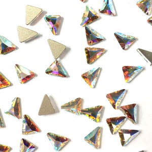 Puede incluir: Surtido de piedras de cristal triangulares iridiscentes sobre un fondo blanco.