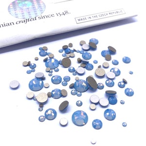 May include: A scattering of light blue iridescent rhinestones and silver adhesive backs. Bohemian crafted since 1548. Made in the Czech Republic.
