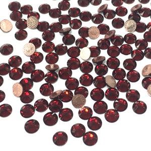 May include: A scattering of small, round, red rhinestones. The rhinestones have a faceted, reflective surface.