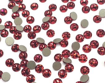 May include: A scattering of red rhinestones on a white background. The rhinestones are small and round, with a shiny, faceted surface.