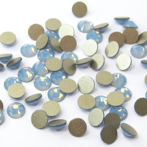 May include: A scattering of light blue iridescent rhinestones with a silver backing. The rhinestones are round and have a faceted design.