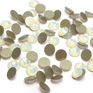 May include: A scattering of iridescent white opal rhinestones with silver backs. The rhinestones are round and have a faceted surface.