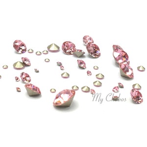 Puede incluir: Un conjunto de pedrería rosa de varios tamaños dispersos sobre una superficie blanca. La pedrería tiene un corte facetado, reflejando la luz. Algunos tienen un respaldo plateado. La imagen incluye el texto "My Chobos".