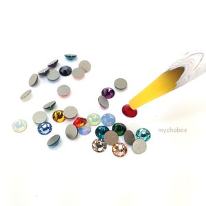 Puede incluir: Surtido de piedras de cristal de colores y piedras de cristal transparentes con una herramienta amarilla para aplicar piedras de cristal.