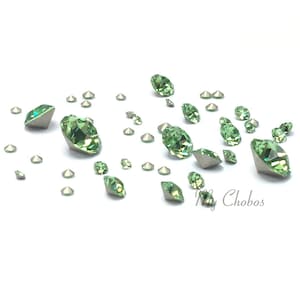 Puede incluir: Surtido de piedras de cristal verdes de varios tamaños, esparcidas sobre un fondo blanco.
