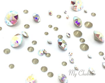Puede incluir: Surtido de piedras de cristal transparente iridiscente de varios tamaños esparcidas sobre un fondo blanco. Las piedras tienen un efecto arcoíris.
